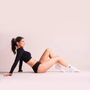 Frau sitz auf dem Boden und trägt schwarze Periodenunterwäsche Feel-Good-Daily mit sportlichem Oberteil.