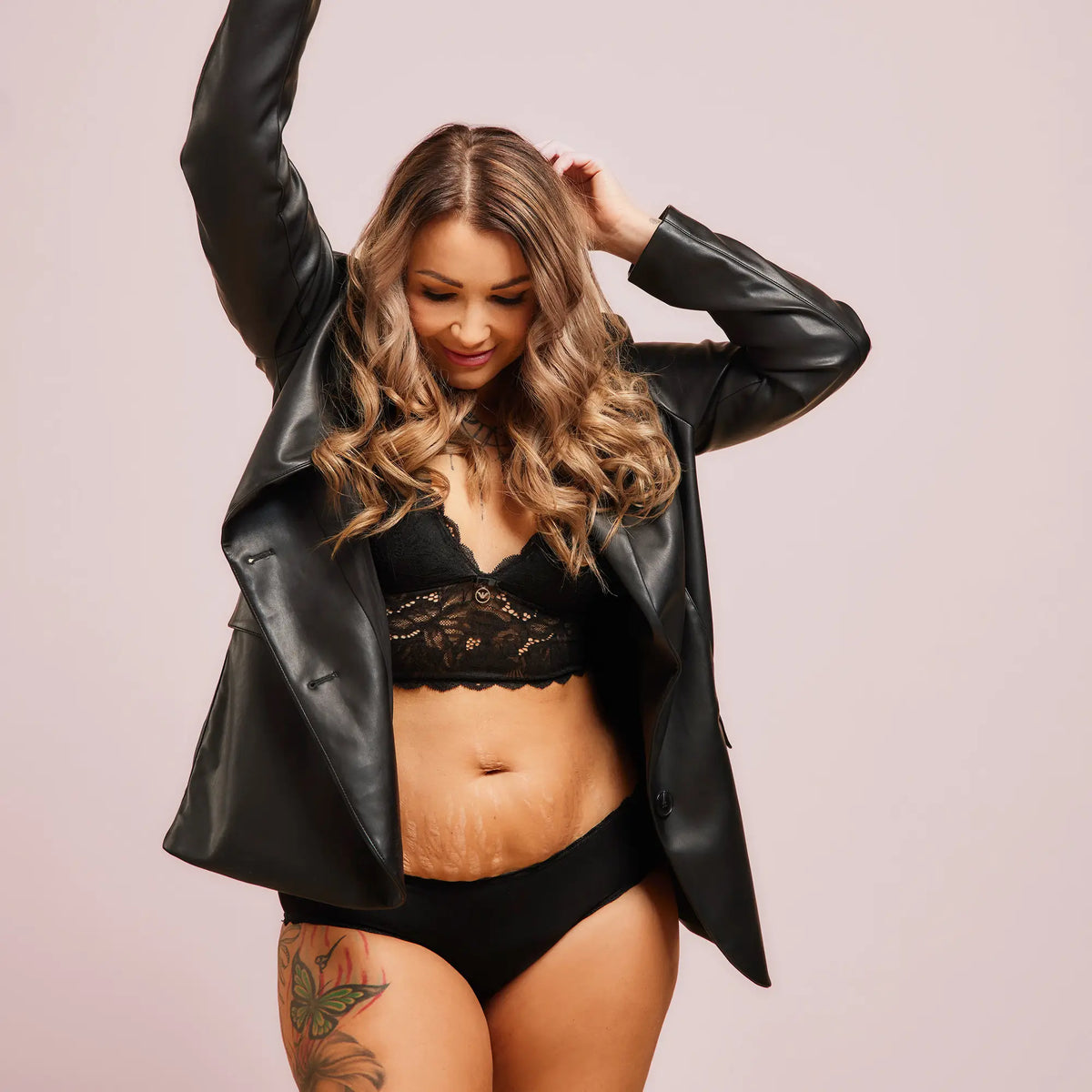 Woman wearing the black Comfy Brief period panty with a lace bra, smiling.