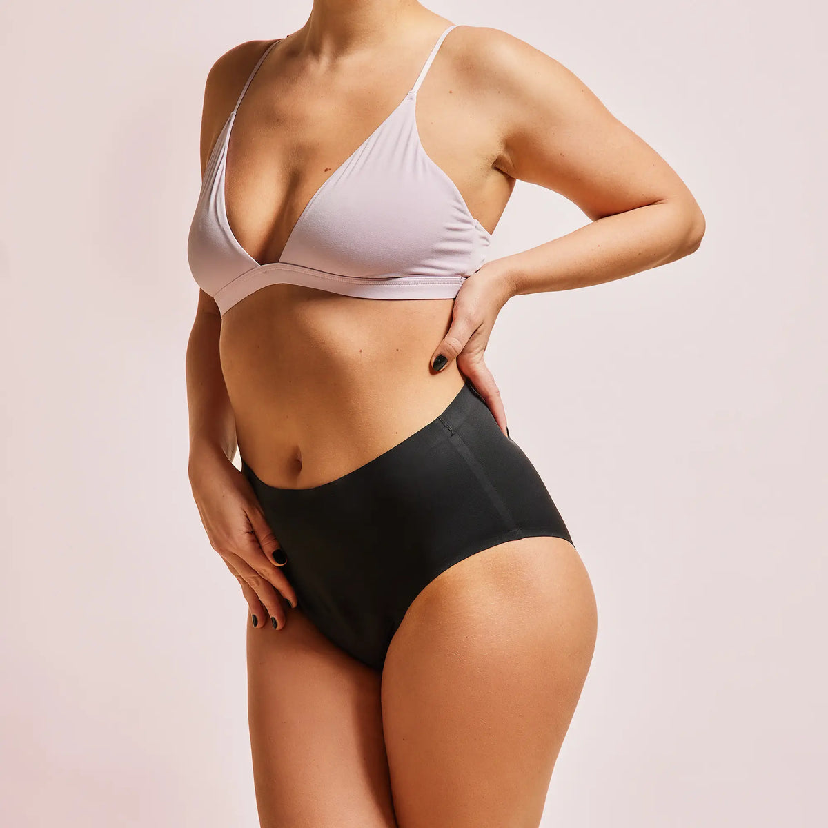Frau trägt schwarze Periodenunterwäsche Seamless-High-Waist mit hellem BH.