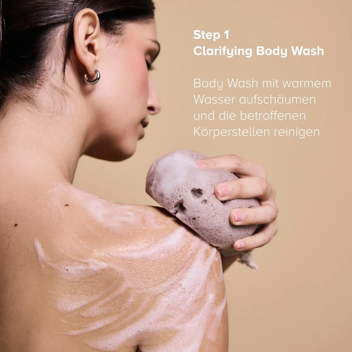 Step 1 of the Clarifying Body Duo: woman lathering the Clarifying Body Wash on her shoulder with a sponge