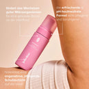 Rosa Intimate-Cleansing-Foam steht aufrecht an einer menschlichen Haut.
