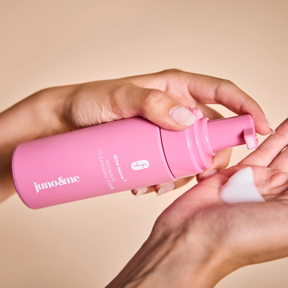 Woman holding the pink Intimate Cleansing Foam and dispensing foam into her other hand
