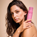 Frau hält Intimate-Cleansing-Foam auf ihrer Schulter und guckt in die Kamera.
