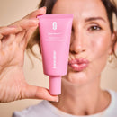 Frau hält Intimate-Prebiotic-Cream in zwei Fingern und macht einen Kussmund.